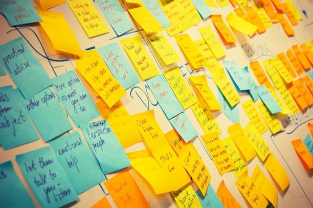 Noticeboard covered with hundreds of yellow post-it to-do notes on it 